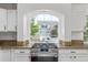 Kitchen with stainless steel gas range and a view of the front yard through an arched window at 5403 Odessa St, Denver, CO 80249