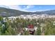 Aerial view of home nestled among tall evergreen trees with mountains in the background at 25531 Mosier Cir, Conifer, CO 80433