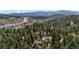 A serene aerial view of a home nestled among lush trees, with a glimpse of the town and mountains in the distance at 25531 Mosier Cir, Conifer, CO 80433