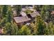 Aerial view of home surrounded by trees, featuring roof, outdoor deck, and stairway at 25531 Mosier Cir, Conifer, CO 80433