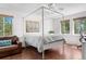 Bright bedroom with a four poster bed, wood floors, and three windows at 25531 Mosier Cir, Conifer, CO 80433