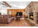 A cozy living room featuring a stone fireplace, wood-paneled walls, hardwood floors and a comfortable leather sofa at 25531 Mosier Cir, Conifer, CO 80433