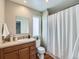 Well-lit bathroom features wood cabinet vanity, toilet, shower with curtain, and large mirror at 4723 Crestone Peak St, Brighton, CO 80601