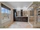 Spacious bathroom with double vanities, dark wood cabinets, travertine tile, and glass shower at 13955 Craig Way, Broomfield, CO 80020