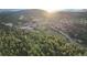 Wide aerial view of a school and sports fields nestled amongst rolling hills and dense green forests under a bright sky at 5077 Camel Heights Rd # C, Evergreen, CO 80433