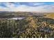 Stunning aerial view of a serene lake surrounded by vibrant green forests and rolling hills under a partly cloudy sky at 5077 Camel Heights Rd # C, Evergreen, CO 80433