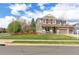 Two-story home featuring charming red shutters, an inviting porch, a well-manicured lawn, and mature trees at 2901 Madison Ln, Broomfield, CO 80023