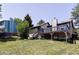 Expansive green backyard with mature trees and an elevated deck on a sunny day at 3328 S Danube St, Aurora, CO 80013