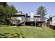 Exterior of home displaying a large backyard with a deck, green grass, and mature trees at 3328 S Danube St, Aurora, CO 80013