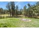 Spacious backyard with lush trees, a decorative garden feature, and a charming wooden fence at 35550 Running Brook Ln, Elizabeth, CO 80107