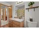 Bright bathroom with a white sink, a decorative mirror, a toilet, and a shower with a leaf-patterned curtain at 35550 Running Brook Ln, Elizabeth, CO 80107