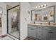 Modern bathroom with a double sink vanity, large framed mirror, and a glass-enclosed shower featuring decorative tile at 35550 Running Brook Ln, Elizabeth, CO 80107
