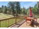Inviting outdoor deck with wooden furniture, an umbrella, and picturesque views of the surrounding trees and landscape at 35550 Running Brook Ln, Elizabeth, CO 80107