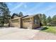 Detached two car garage featuring stone accents and ample driveway space, nestled among mature trees at 35550 Running Brook Ln, Elizabeth, CO 80107