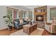 Comfortable living room featuring a stone fireplace, cozy seating, and natural light streaming through the windows at 35550 Running Brook Ln, Elizabeth, CO 80107