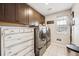 Well-lit laundry room featuring washer, dryer, built-in cabinets, and decorative chest of drawers at 1669 Stable View Dr, Castle Pines, CO 80108