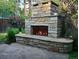 Outdoor stone fireplace with flagstone hearth and decorative stone chimney, surrounded by lush greenery at 732 Poplar St, Denver, CO 80220
