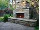 Outdoor stone fireplace in a backyard setting, surrounded by lush greenery and landscaping at 732 Poplar St, Denver, CO 80220