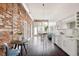 Open living space with a kitchen, dining area, exposed brick, and wood floors at 1810 E 33Rd Ave, Denver, CO 80205