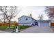 Charming light-blue home featuring an attached garage, well-maintained lawn and mature trees at 5389 W Roxbury Pl, Littleton, CO 80128