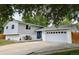 Split-level home with a two-car garage, blue double front doors, and manicured landscaping at 5389 W Roxbury Pl, Littleton, CO 80128