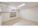 Well-lit basement features neutral carpet and shelving, offering versatile space for storage or customization at 12218 Monroe Dr, Thornton, CO 80241