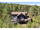Aerial view of a two-story home nestled in a lush wooded area, complete with a deck at 2976 Hiwan Dr, Evergreen, CO 80439