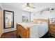 Cozy bedroom with a wooden bed frame, ceiling fan, large mirror, and view of the surrounding trees at 2976 Hiwan Dr, Evergreen, CO 80439
