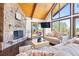 Comfortable living room with a cozy stone fireplace, vaulted ceilings, and access to deck at 2976 Hiwan Dr, Evergreen, CO 80439