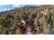 Aerial view of a multi-story cabin with a deck nestled among trees and mountains at 31207 Kings Valley Dr, Conifer, CO 80433