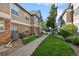 Exterior view of a townhome with stone accents and neutral siding, surrounded by lush greenery and a sidewalk at 4385 S Balsam St # 3-101, Littleton, CO 80123