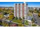 Tall brick and white condo building surrounded by fall foliage, with a glimpse of the city skyline in the background at 3131 E Alameda Ave # 2002, Denver, CO 80209