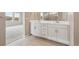 Elegant bathroom featuring a large white vanity with double sinks, beige tile flooring and neutral colored walls at 39751 Congress Ln, Elizabeth, CO 80107