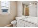 Well-lit bathroom features a white vanity, toilet, and shower, complemented by a large mirror and window at 39751 Congress Ln, Elizabeth, CO 80107