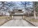 Two-car garage with concrete driveway and stone retaining wall and manicured landscaping at 1590 S Milwaukee St, Denver, CO 80210