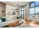 Open living room featuring hardwood floors, large windows, modern furniture, and a partial view of the kitchen at 3100 Huron St # 3E, Denver, CO 80202