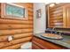 Charming bathroom featuring log walls, a custom sink, and a bright window with lovely views of nature at 29477 Blue Moon Dr, Evergreen, CO 80439