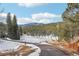 Scenic driveway leading to the home, surrounded by trees and snow, with a mountain view in the distance at 29477 Blue Moon Dr, Evergreen, CO 80439