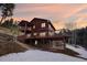 Log home with multiple decks and stone accents, offering stunning views of the surrounding landscape at sunset at 29477 Blue Moon Dr, Evergreen, CO 80439