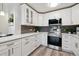 Modern white kitchen with stainless steel appliances and gray tile backsplash at 715 S Alton Way # 5A, Denver, CO 80247