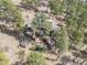 Aerial view of a home nestled in the trees with spacious decks, outdoor seating and firewood storage at 7395 Heiter Hill Dr, Evergreen, CO 80439