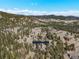 Expansive aerial view of mountain home with beautiful hillside scenery, trees and blue skies at 7395 Heiter Hill Dr, Evergreen, CO 80439