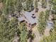 Aerial view of a beautiful home with a roof with long driveway winding through the trees at 7395 Heiter Hill Dr, Evergreen, CO 80439