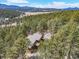 Scenic aerial view of home surrounded by lush forests with mountain range in the distance at 7395 Heiter Hill Dr, Evergreen, CO 80439