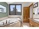 Bathroom featuring soaking tub with tile surround, natural light, and wood-trimmed accents at 7395 Heiter Hill Dr, Evergreen, CO 80439