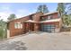 Beautiful two-story home with brown wood exterior and a contemporary glass-paneled garage door at 7395 Heiter Hill Dr, Evergreen, CO 80439