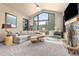 Bright living room boasts vaulted ceiling, large windows with wooded views, and a stone fireplace at 7395 Heiter Hill Dr, Evergreen, CO 80439