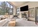 Cozy living room featuring a stone fireplace, large windows offering beautiful wooded views, and comfortable seating at 7395 Heiter Hill Dr, Evergreen, CO 80439