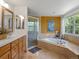 Spa bathroom featuring double sinks, glass shower, soaking tub, and a large window for natural light at 8953 W Brandt Pl, Littleton, CO 80123