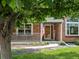 Charming brick home with a welcoming front porch, American flag, and a well-manicured lawn at 8953 W Brandt Pl, Littleton, CO 80123